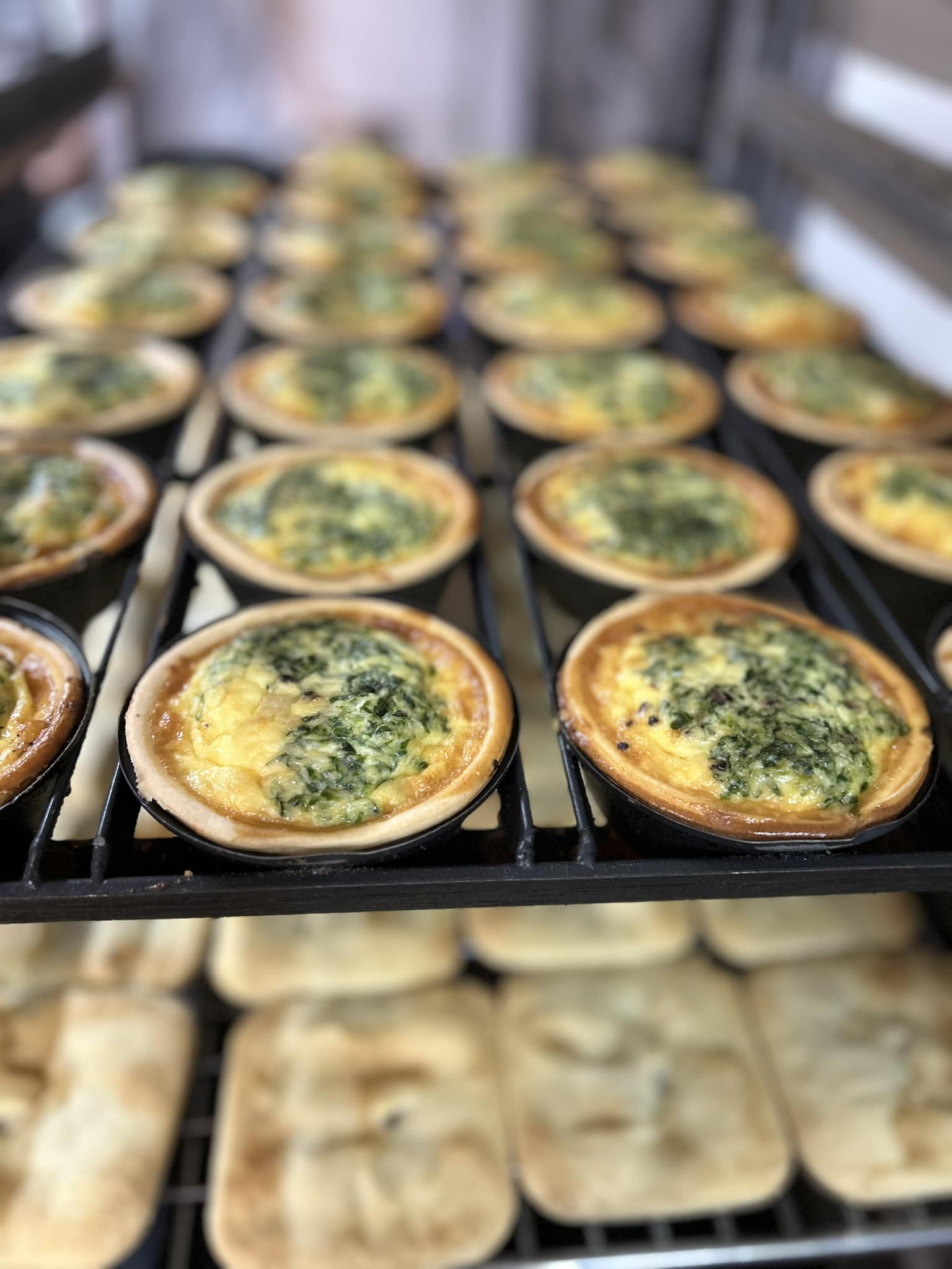 Spinach and cheese quiches cooling on bakery racks