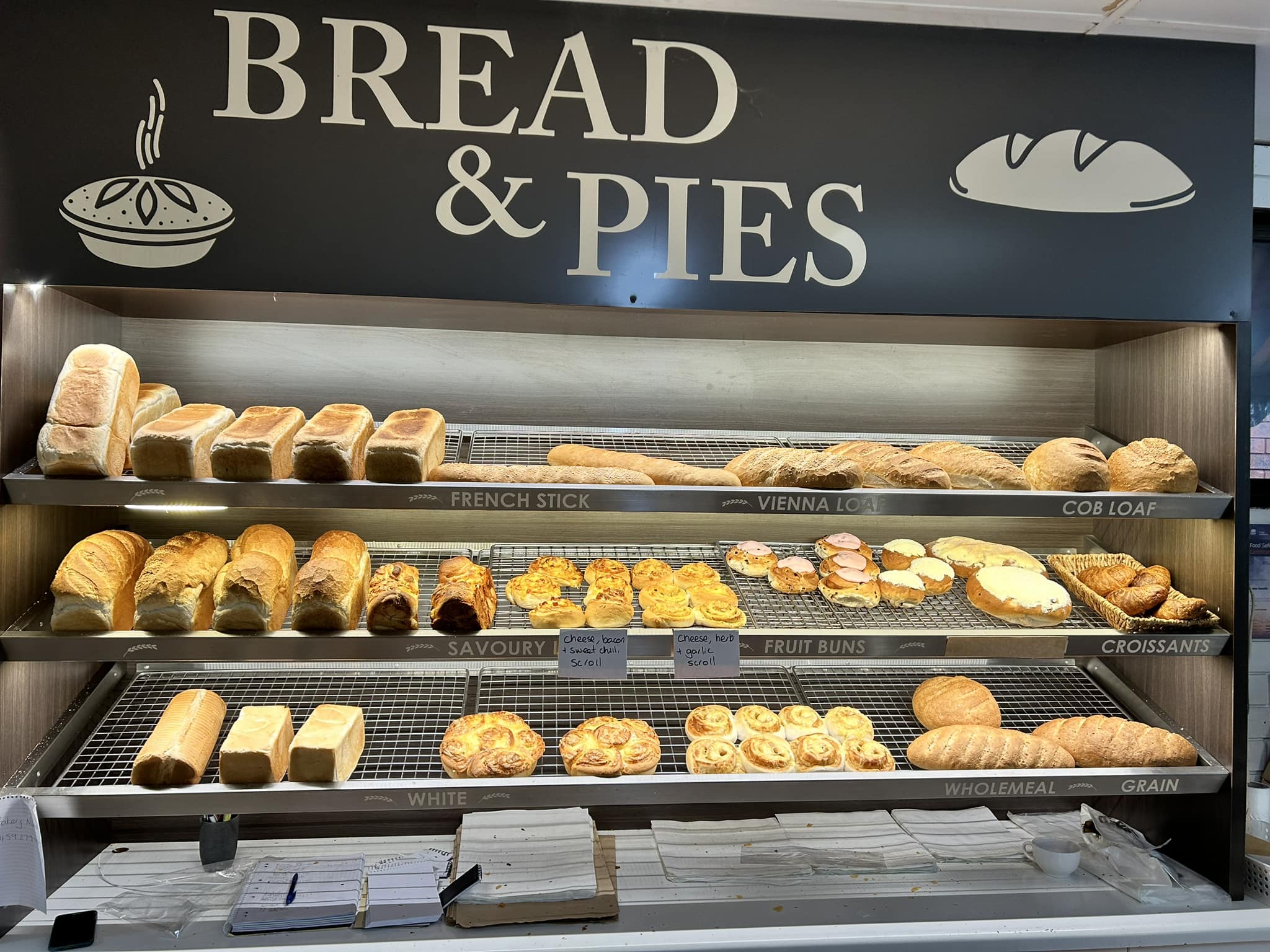The in-store bread and pies shelves, stocked with labelled loaves and rolls